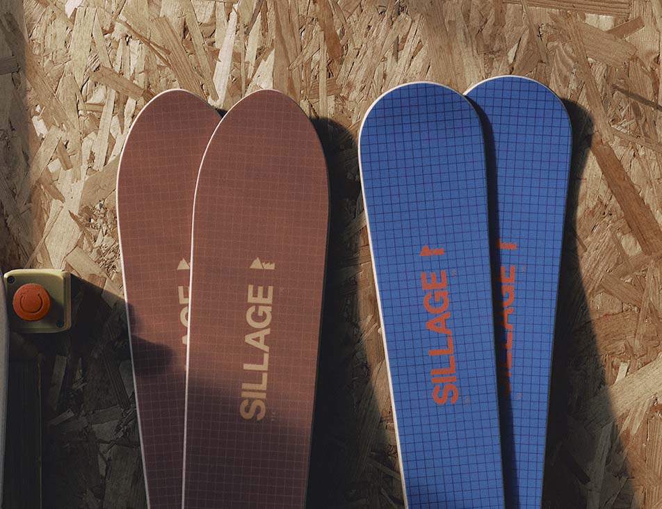Deux paires de skis Sillage posées sur un panneau de bois